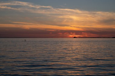 İsveç 'te yaz boyunca sakin körfez suyunda sörf tahtasında nükleer enerji santrali Barseback görünür bir şekilde duran bir adam.
