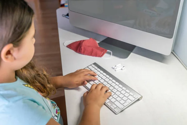 blonde caucasian girl using a computer in her bedroom to study online for the covid-19 pandemic Concept of distance education.