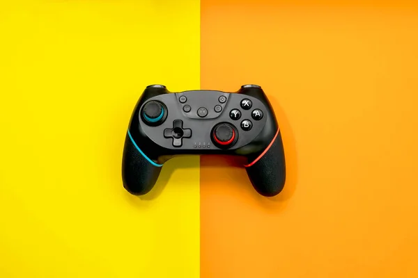 Video game competition. Game concept. Black joystick on pastel yellow and orange background.