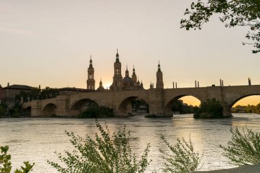 Taş köprü ve San Lazaro parapeti ile Ebro nehri ve Nuestra Katedrali bazilikası Senora del Pilar de Zaragoza günbatımında, İspanya