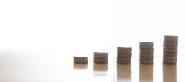 Beyaz arka planı olan bir masanın üstünde beş adet bozuk para kulesi.