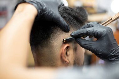 Adam berber dükkanında tıraş oluyor.