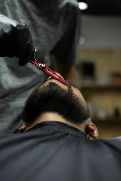man's beard cut with scissors in barbershop , personal care concept