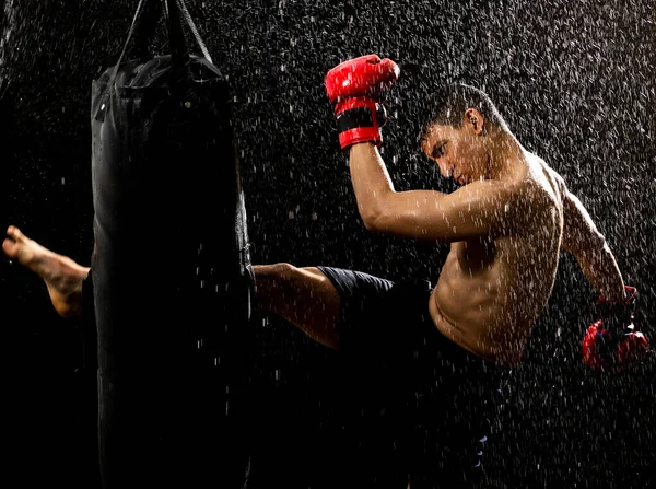 man with red gloves training with a punching bag in the rain