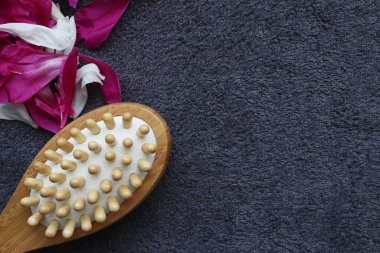 Spa evi. Gri havlunun arka planında masaj fırçası ve şakayık yaprakları