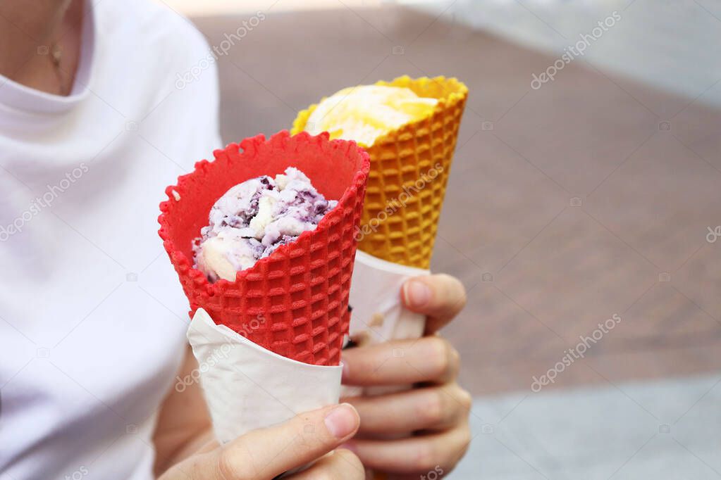 woman holding waffle cups with ice cream in her hands.