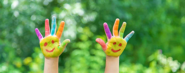 Children\'s hands in the colors of summer. Selective focus.