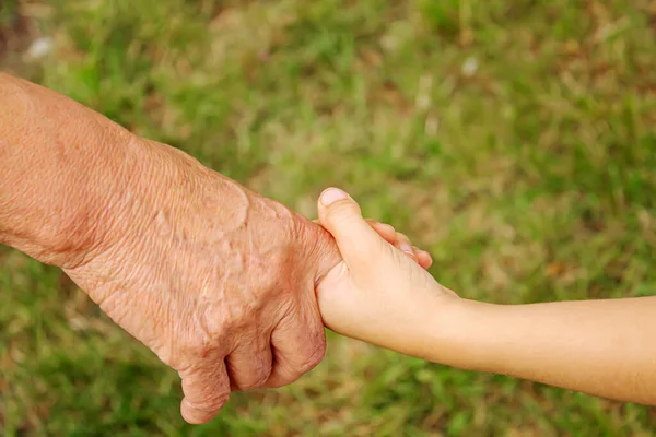 Un anciano con manos de niños. enfoque selectivo —  Fotos de Stock