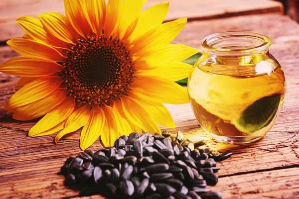 Sunflower seeds and oil bottle on old wooden background. Selective focus — Stock Photo, Image