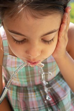 Çocuklar pınardan su içer. Seçici odaklanma. Doğa.