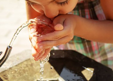 Çocuklar pınardan su içer. Seçici odaklanma. Doğa.