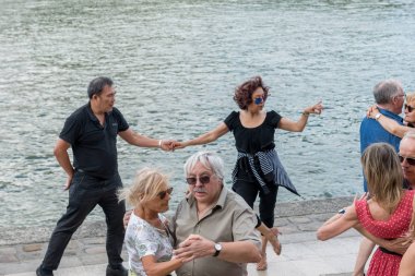 Paris'teki Seine Nehri'nin kıyısında dans eden yaşlı insanlar. 10 Ağustos 2019 Paris, Fransa. 
