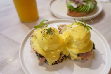 Tütsülenmiş somon, hollandaise sosu ve ahşap masada soğan soslu nefis bir Benedict yumurtası..