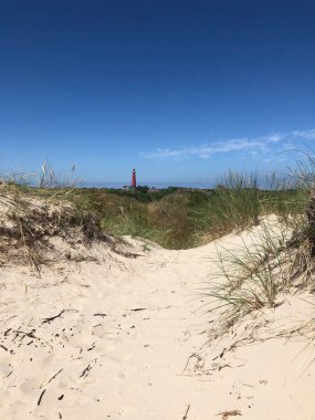 Hollanda 'daki Schiermonnikoog' un arka planında deniz feneri olan kum tepeciği