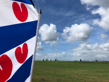 Frisian flag with skutsjesilen in the background in Friesland, The Netherlands clipart