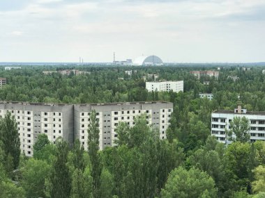 Pripyat 'taki binalar. Arka planda Çernobil santrali olan terk edilmiş şehir.
