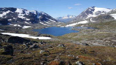 Norveç 'teki Jotunheimen Ulusal Parkı' nda dağların önünde karlı göl