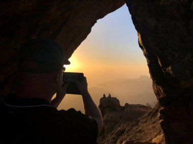 Gün batımında Roque Nublo 'da fotoğraf çeken adam. Gran Canaria adasındaki volkanik kaya.