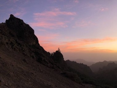 Roque Nublo 'da gün batımı ve pembe gökyüzü. Gran Canaria adasındaki volkanik kaya.