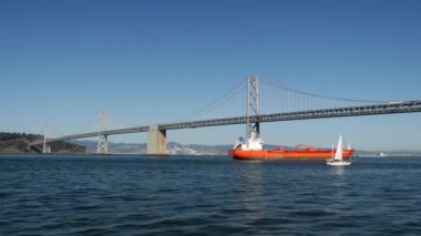 Kargo gemisi ve yelkenli San Francisco Oakland Bay Köprüsü 'nde.