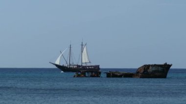 Aruba açıklarında bir gemi enkazının yanından geçen yelkenli gemi.