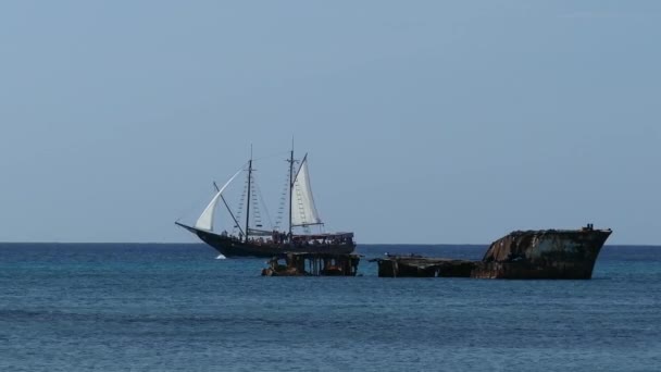 Voilier passant devant une épave au large des côtes d'Aruba