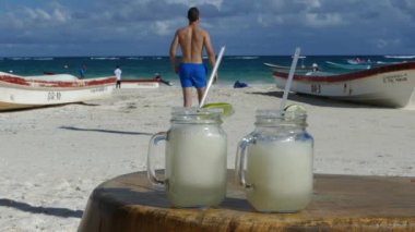 Seksi erkekler Meksika, Yucatan 'daki Tulum plajında dondurulmuş iki margaritadan uzaklaşıyor.