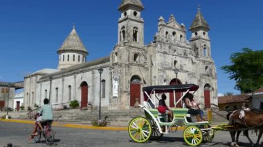 Granada Nikaragua 'daki Guadalupe Kilisesi' nden geçen at arabalı turistler.