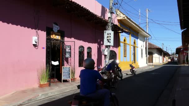 尼加拉瓜格拉纳达一条五彩斑斓的街道上经过的自行车和摩托车 — 图库视频影像