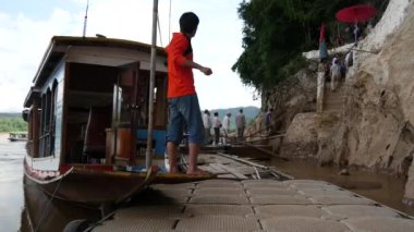 Uzun kuyruklu tekne ve turistler Pak Ou Mağaraları 'na doğru yürüyorlar, Laos.
