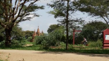 Bagan, Myanmar, Burma 'da Pagodas' ın önünde bisiklet süren bir turist.