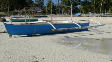 Filipinler 'deki Bohol Adası' ndaki alçak gelgit sırasında sabah Anda sahilinde yansıyan mavi katamaran teknesi.