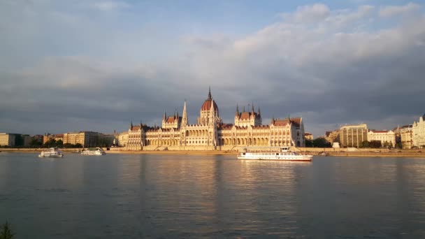 クルーズ船と太陽の反射と夜のハンガリー議会ビル ブダペスト議会 — ストック動画