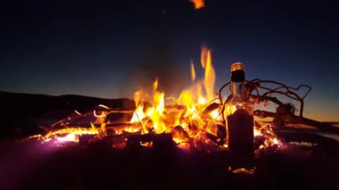 Lefkada Yunanistan sahilinde içi boş bir şişeyle kamp ateşi.