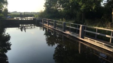 Friesland, Hollanda 'da bir kilidin üzerinden bisikletle geçen insanlar.