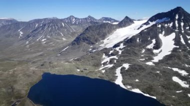 Norveç 'in Jotunheimen Ulusal Parkı' ndaki karlı dağların arasında büyük bir göl.