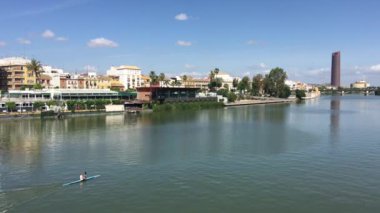 Kanal de Alfonso XIII 'te kano sürerken Sevilla İspanya' nın arka planında Puerto Triana kulesi vardı.