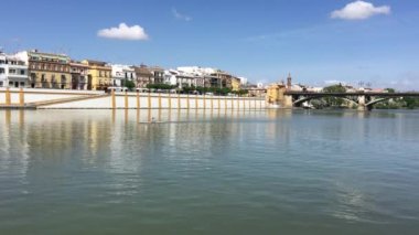 Kanal de Alfonso XIII 'de kano sürerken Sevilla İspanya' nın arka planında Puente de Isabel Köprüsü vardı.