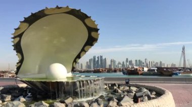 Arkasında Doha silueti olan Dhow Limanı boyunca yer alan İnci Anıtı ve çeşme.