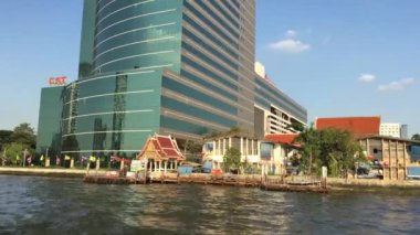 Tayland, Bangkok 'taki Chao Phraya nehri boyunca uzanan bir feribot dolusu binanın görüntüsü.