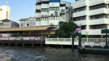 Tayland, Bangkok 'taki Chao Phraya nehri boyunca uzanan bir feribot dolusu binanın görüntüsü.