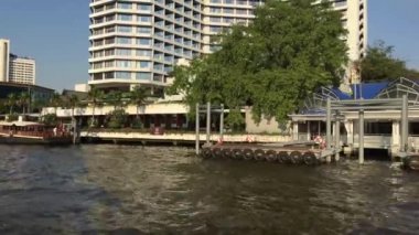 Tayland, Bangkok 'taki Chao Phraya nehri boyunca uzanan bir feribot dolusu binanın görüntüsü.