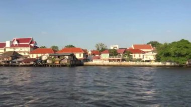 Tayland, Bangkok 'taki Chao Phraya nehri boyunca uzanan bir feribot dolusu binanın görüntüsü.