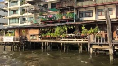 Tayland, Bangkok 'taki Chao Phraya nehri boyunca uzanan bir feribot dolusu binanın görüntüsü.