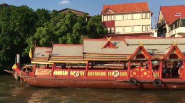 Tayland, Bangkok 'taki Chao Phraya nehri boyunca uzanan bir feribot dolusu binanın görüntüsü.