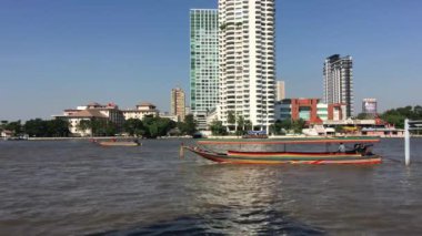 Bangkok 'taki Chao Phraya nehrinde Wat Yannawa Tapınağı manzaralı uzun kuyruklu tekneler.