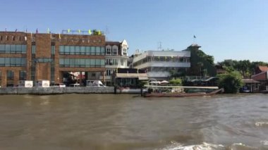 Tayland, Bangkok 'taki Chao Phraya nehri boyunca uzanan bir feribot dolusu binanın görüntüsü.