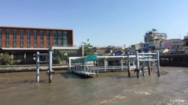 Tayland, Bangkok 'taki Chao Phraya nehri boyunca uzanan bir feribot dolusu binanın görüntüsü.