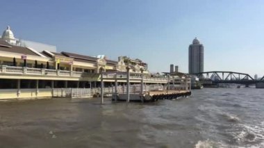 Tayland, Bangkok 'taki Chao Phraya nehri boyunca uzanan bir feribot dolusu binanın görüntüsü.