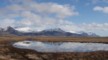 Karlı dağların manzarası gölde yansıyor.